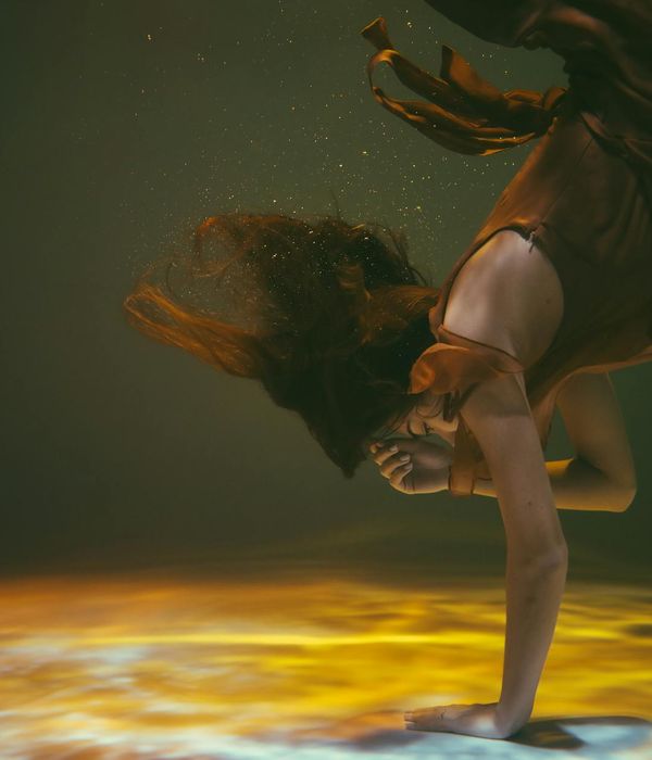 Woman performing a fluid, graceful movement in a calm setting.